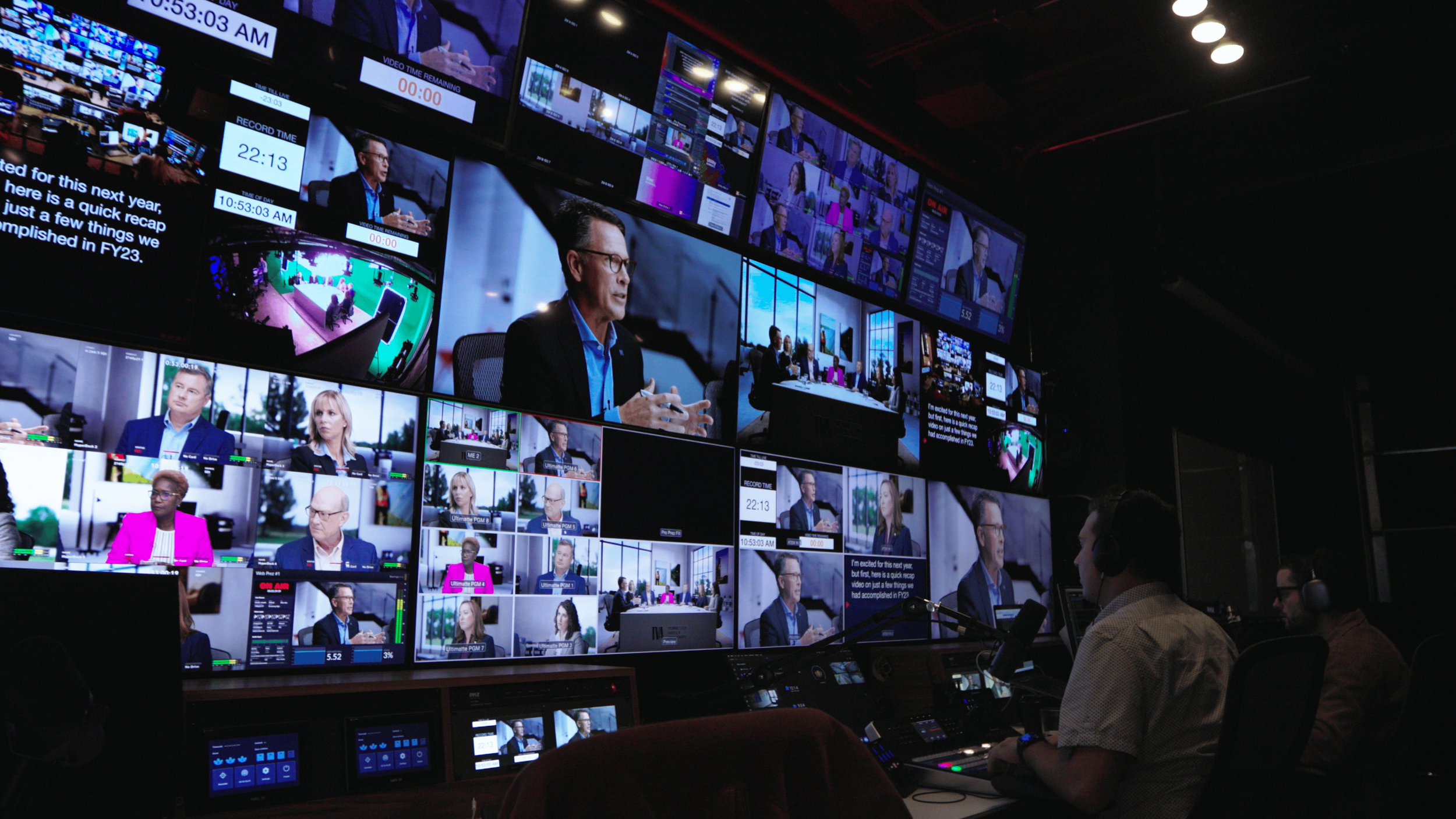 SociallyU’s control room: an operator at the desk in front of a wall of live program monitors