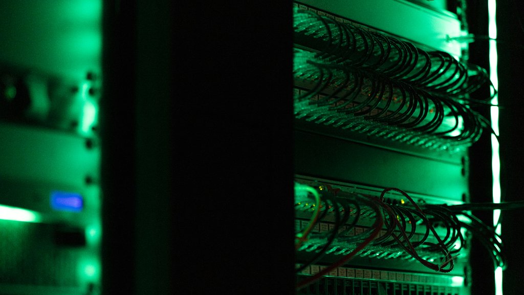 Patch panels in a server rack, cables looping across them under green light