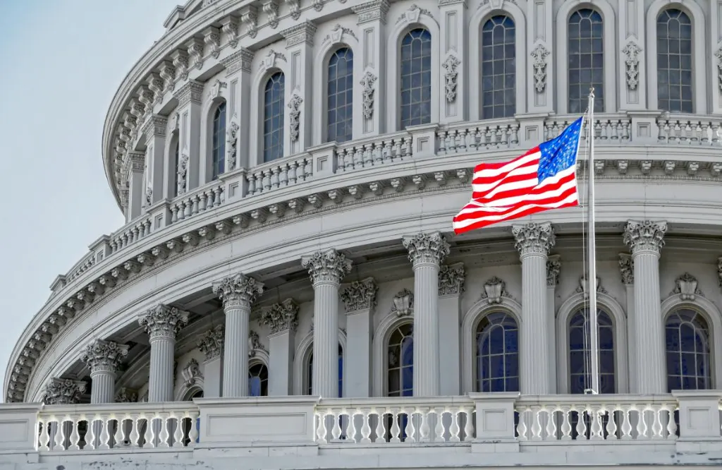 The dome of the United States Capitol with the American flag flying in front of it