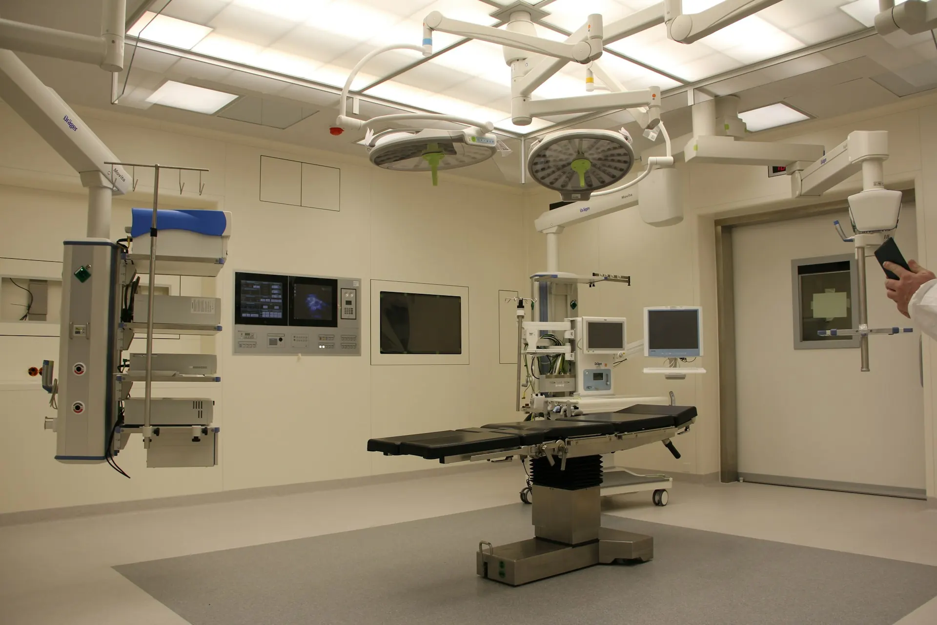 Empty operating room: ceiling-mounted surgical lights, an operating table and wall-mounted displays