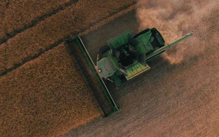 A combine harvester crossing a wheat field, seen from above