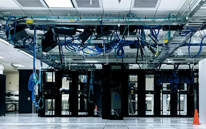 A data hall with cabinet rows on a raised floor under overhead cable trays