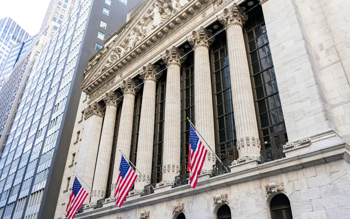 The New York Stock Exchange on Wall Street, American flags along its columns